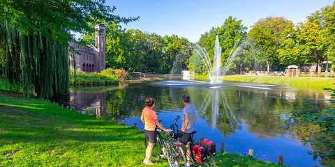 Ein wunderschönes Sommerfoto aus der Stadt Cottbus, auf dem zwei Radler einen Teich am Brandenburgischen Landesmuseum für moderne Kunst bewundern