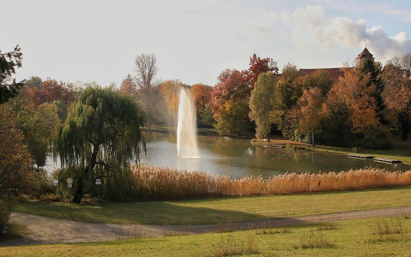 Eine herbstliche Aufnahme zeigt den Schwanenteich, umgeben von farbenfrohen Bäumen. Im Hintergrund erhebt sich das Schloss Spremberg, das die idyllische Szenerie perfekt ergänzt.